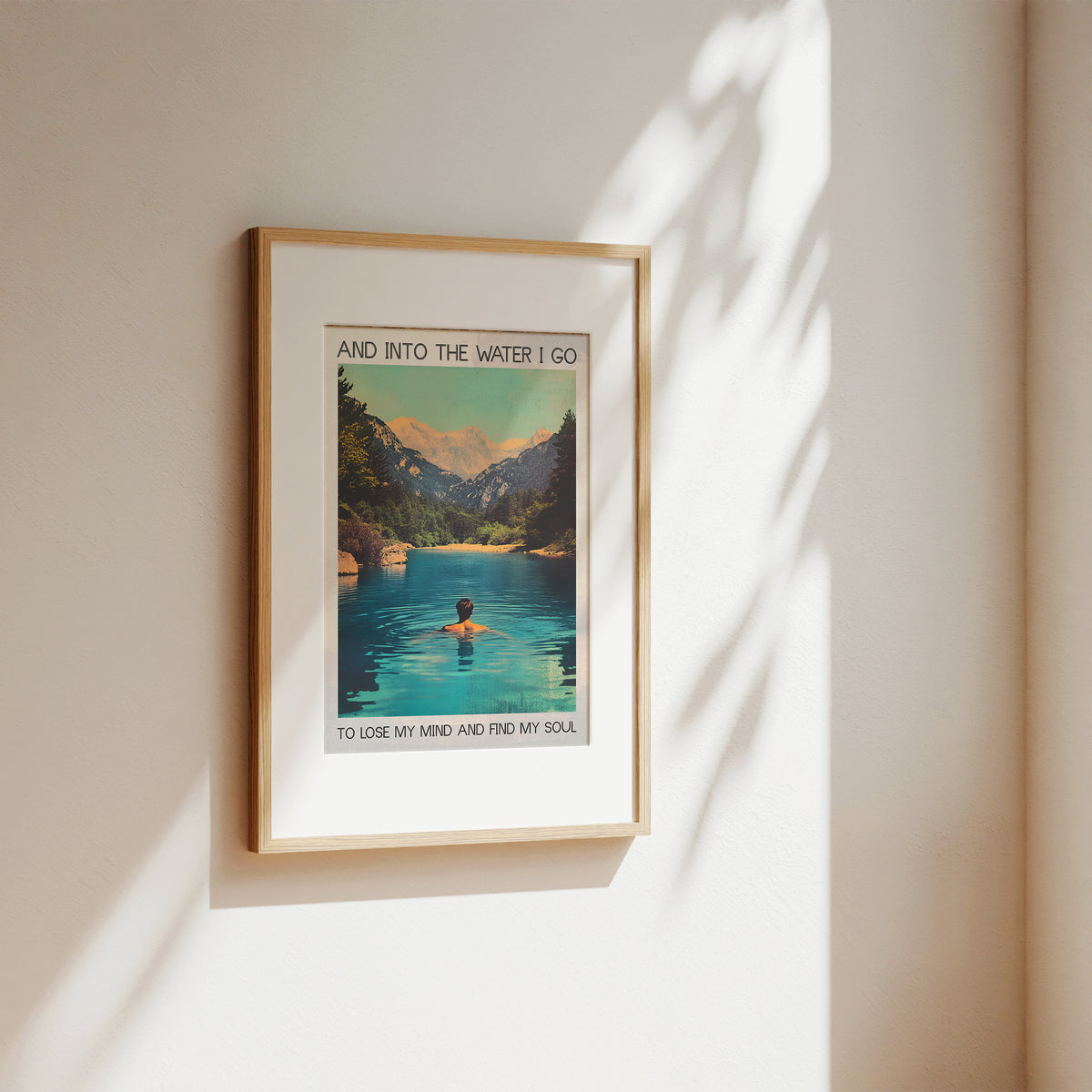 Framed artwork of a person in a lake with mountains, on a beige wall.