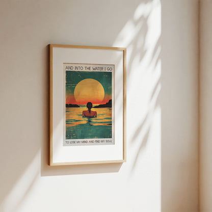 Framed artwork of a person in water with a sunset, on a beige wall.
