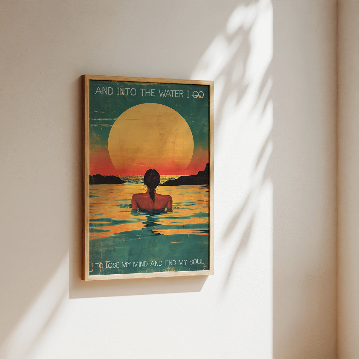Framed artwork of a person in water with a sunset, titled 'And Into The Water I Go'.