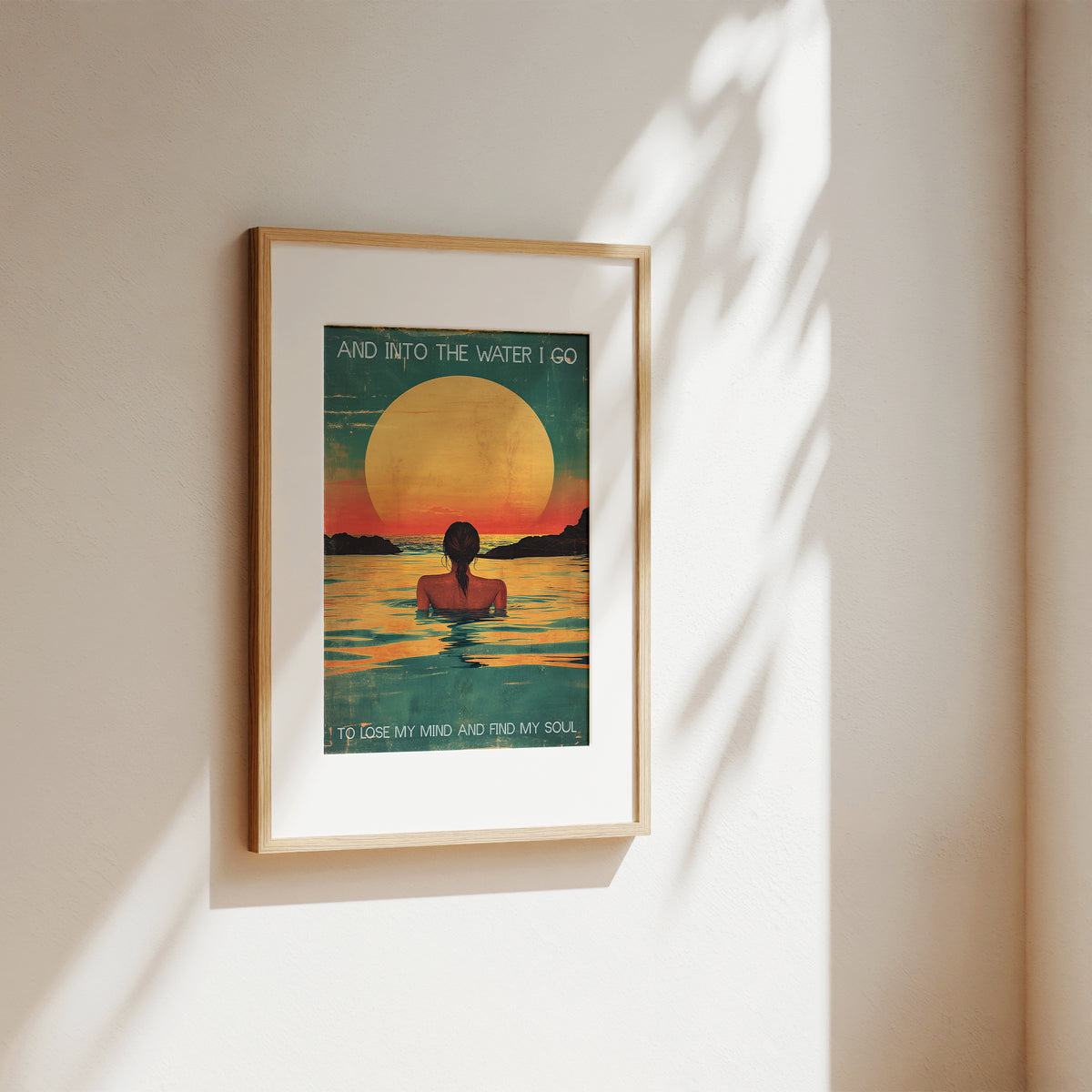 Framed artwork of a person in water with a sunset, on a beige wall.