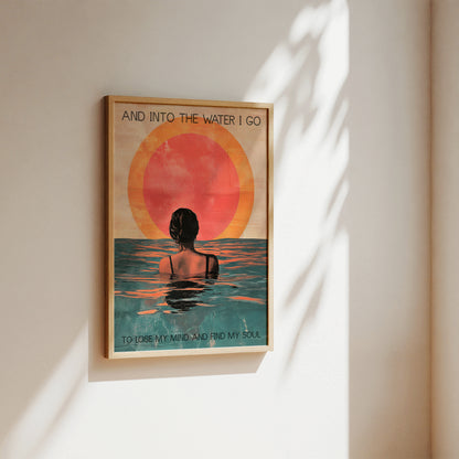 Framed artwork of a person in water with a sunset, on a wall.