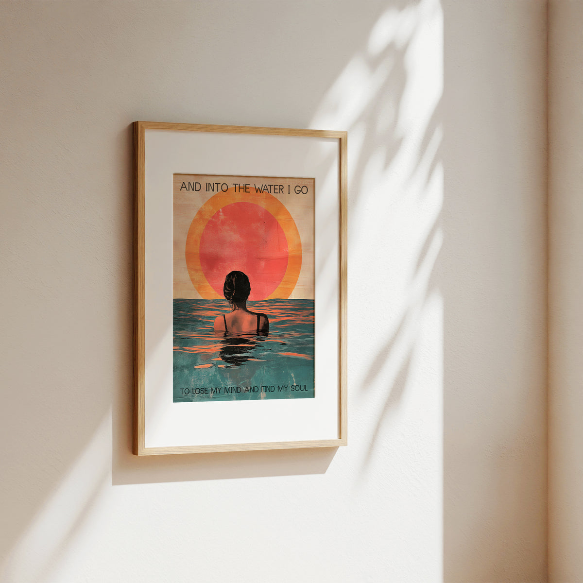 Framed artwork of a person in water with a sunset, on a beige wall.