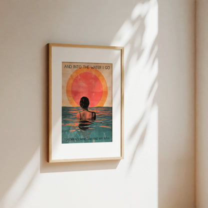 Framed artwork of a person in water with a sunset, on a beige wall.