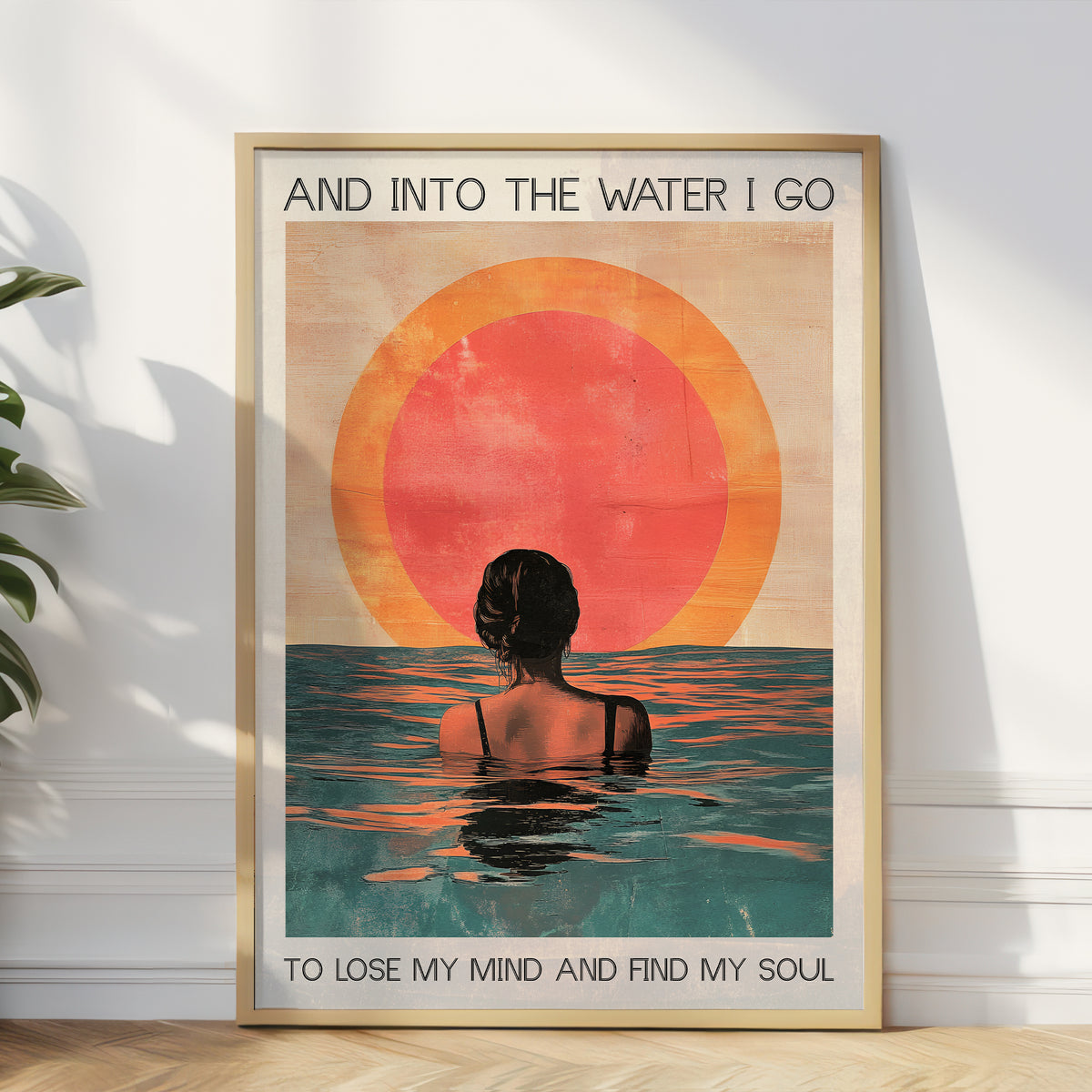 Framed poster with a sunset and person in water design, text 'And into the water I go / To lose my mind and find my soul', on a white wall.