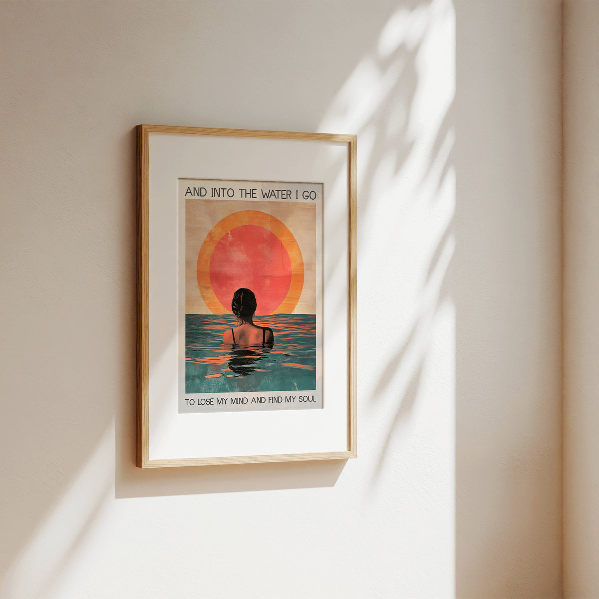 Framed artwork of a person in water with a sunset, on a beige wall.
