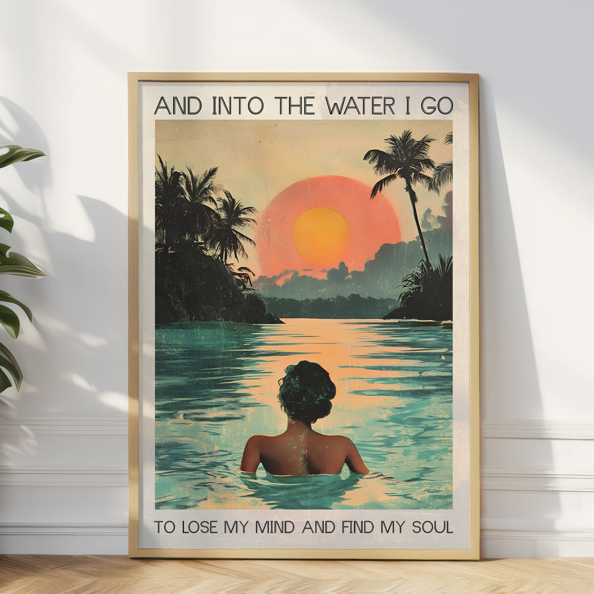 Framed poster of a woman in water with a sunset and palm trees, text 'And into the water I go / To lose my mind and find my soul'.