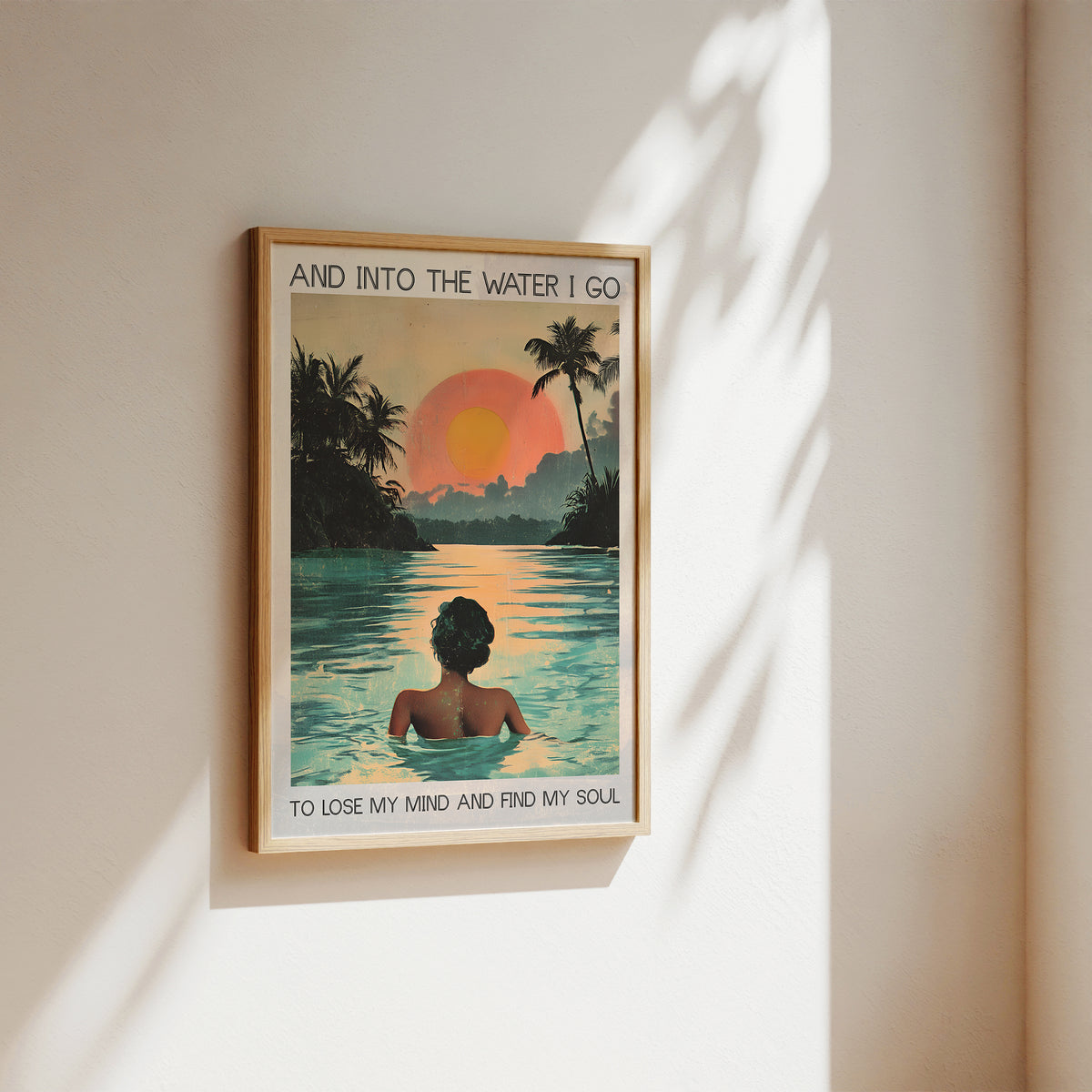 Framed artwork of a person in a pool with a sunset and palm trees, text 'And into the water I go to lose my mind and find my soul'.