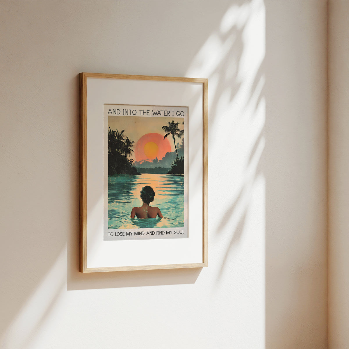 Framed artwork of a person in a pool with a sunset and palm trees, on a beige wall.