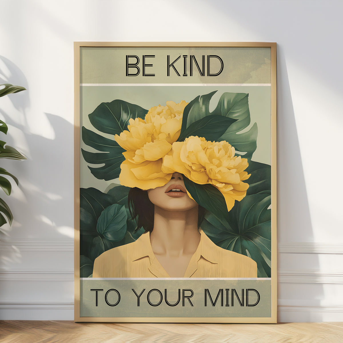 Framed artwork with a woman wearing yellow flowers covering her eyes, surrounded by green leaves, with text 'Be Kind to Your Mind' on a light background.