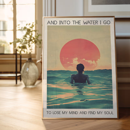 Framed poster of a person in water with a sunset, placed on a wooden floor.