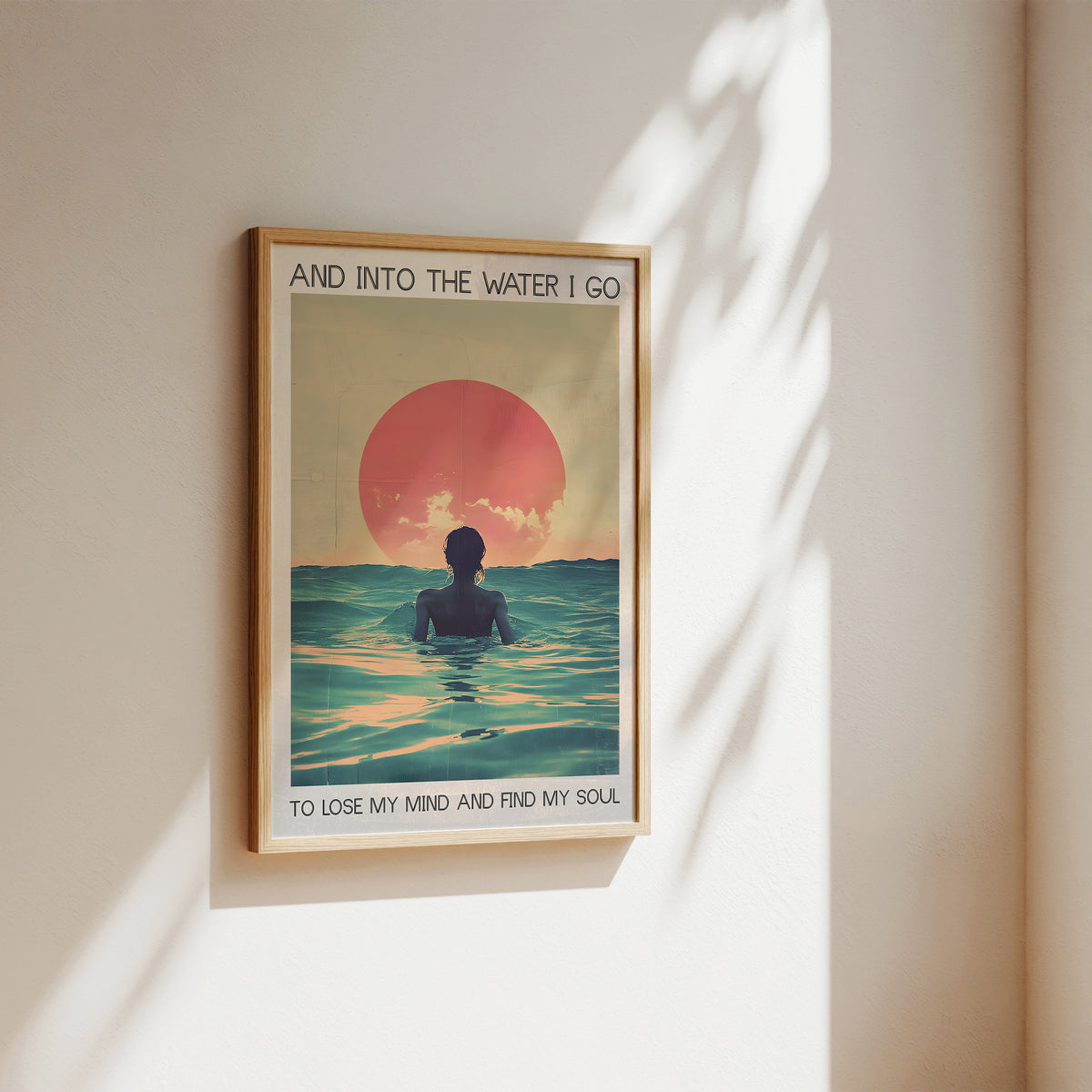 Framed artwork of a person in the water with a sunset, on a beige wall.