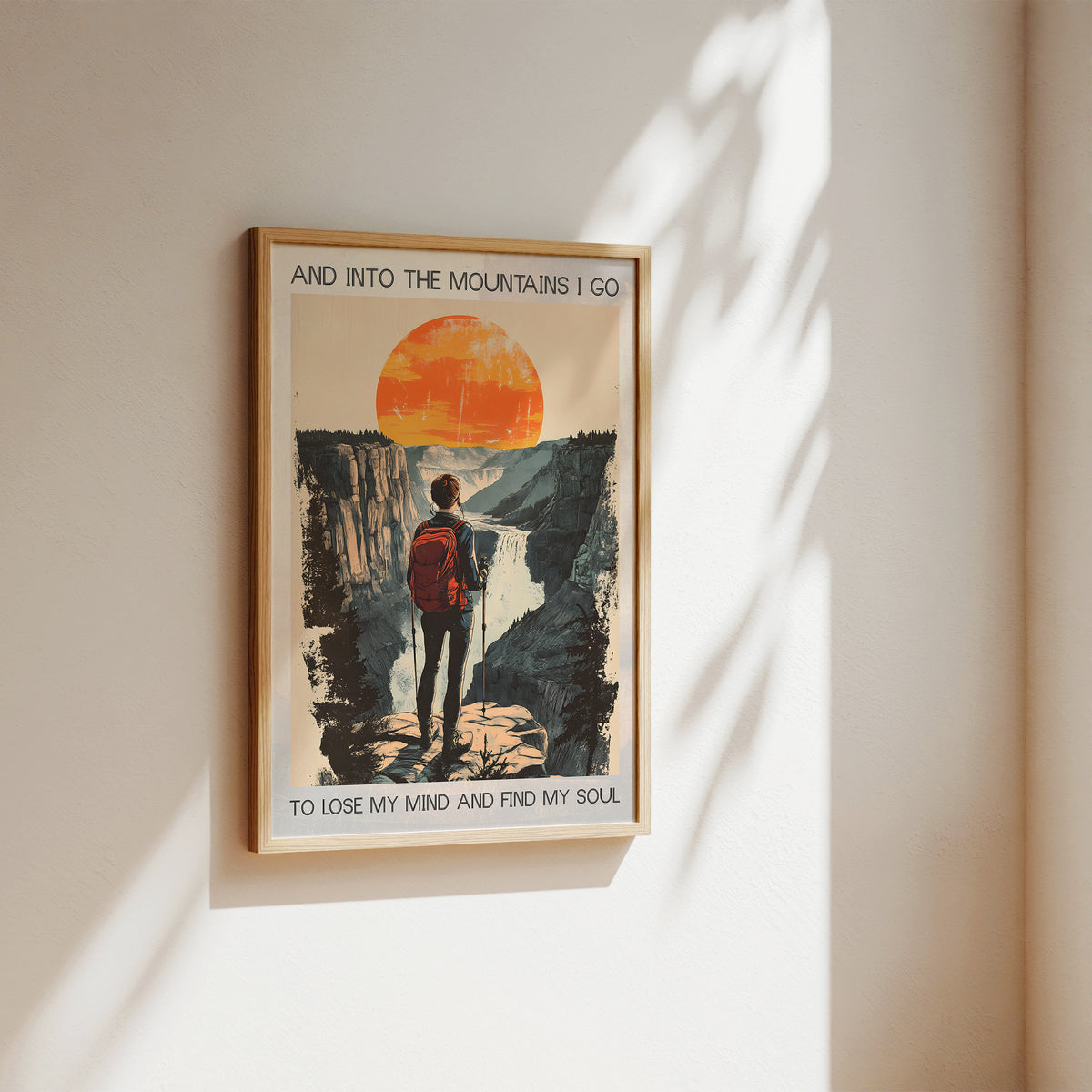 Framed poster of a person in a red jacket standing on a mountain with a sunset, hanging on a wall.