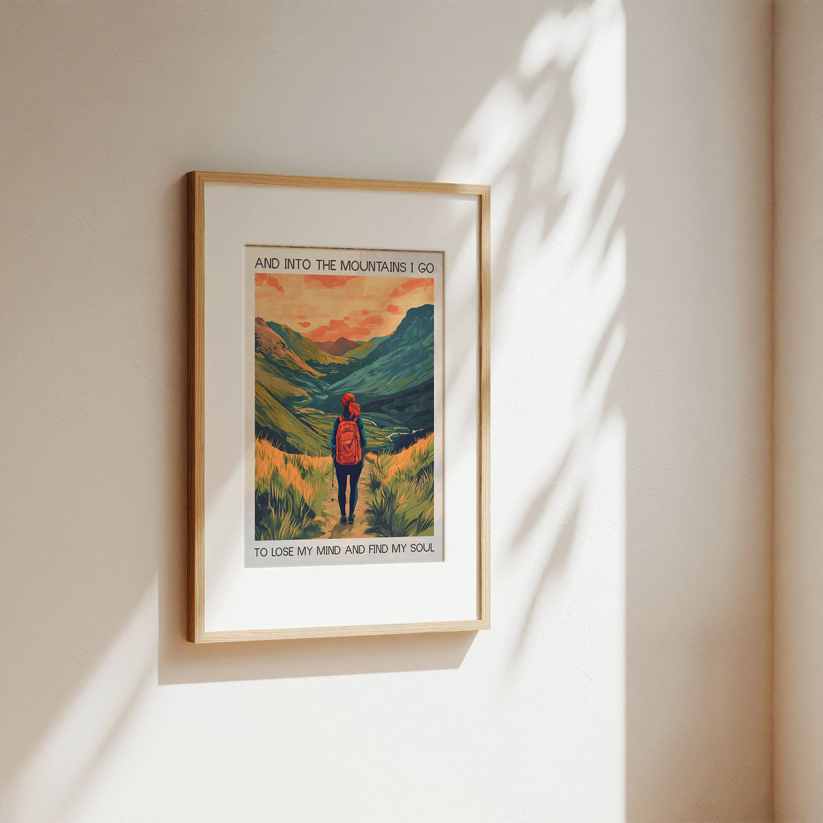 Framed artwork of a mountain scene with a person and text on a beige wall.