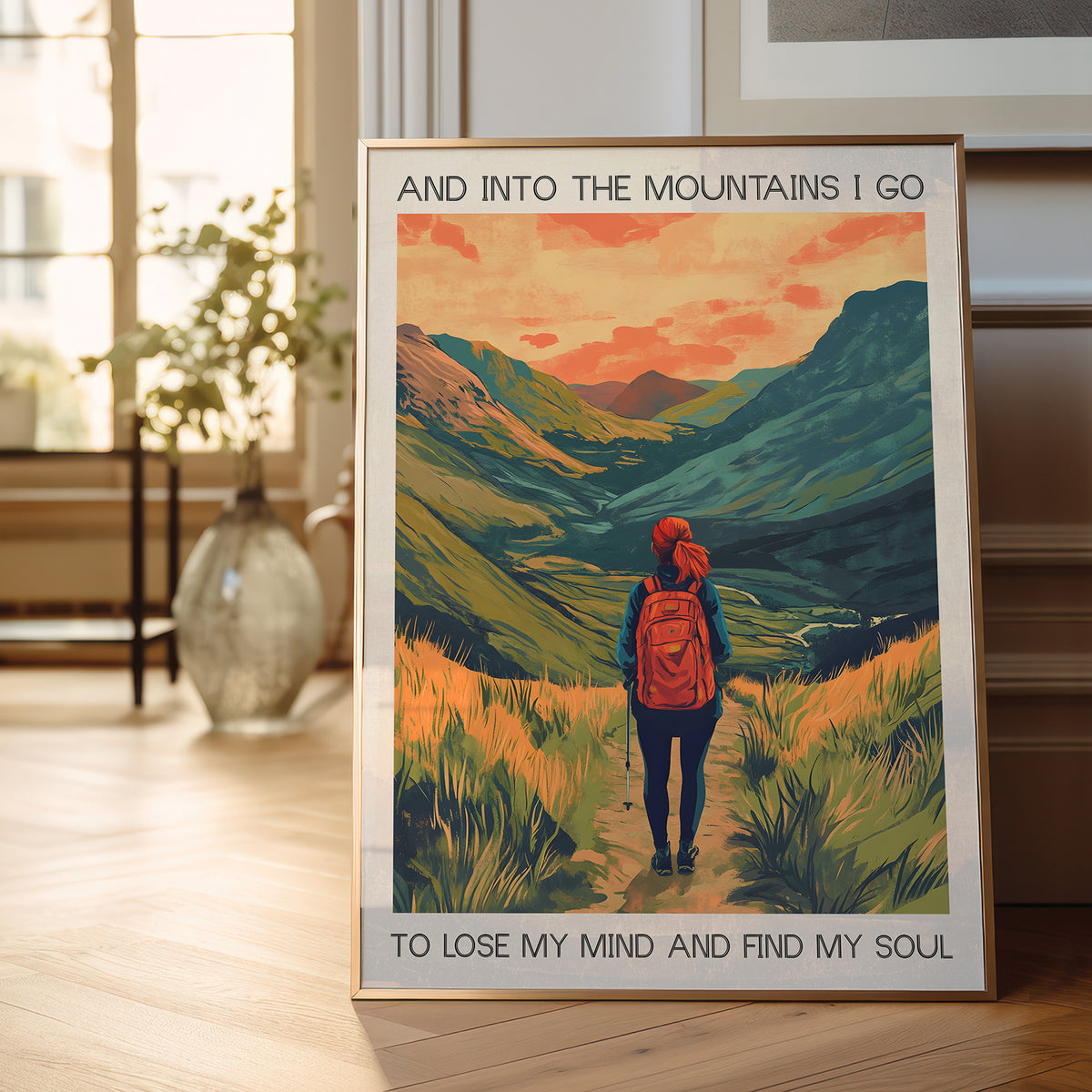 Framed poster of a person hiking with mountains in the background, placed on a wooden floor.