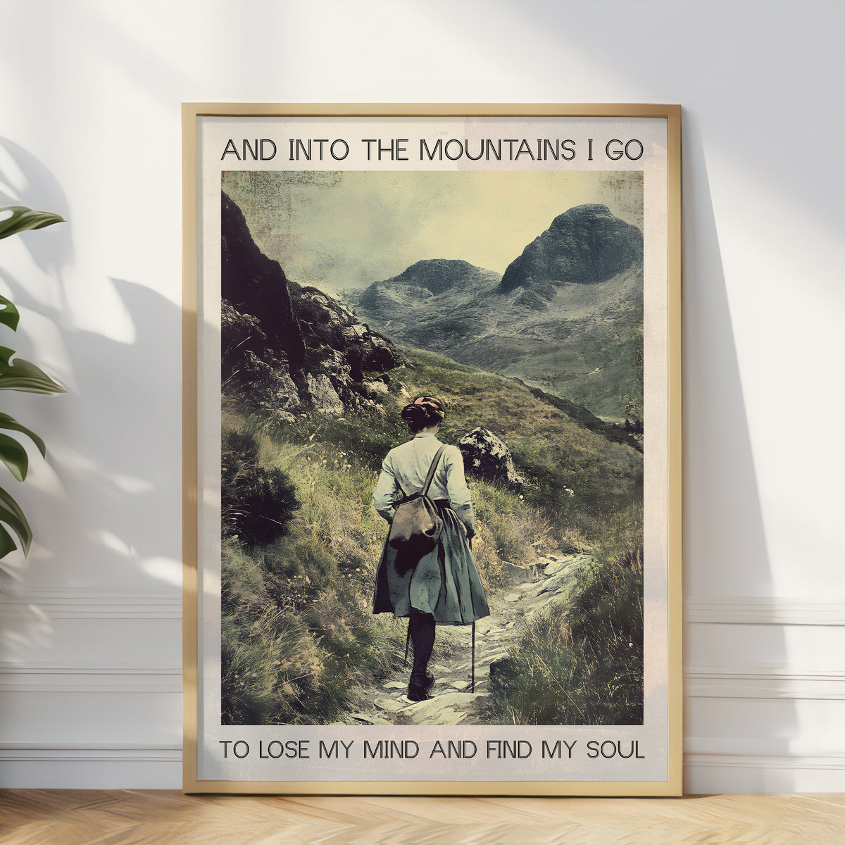 Framed artwork of a person walking on a mountain path with text 'And into the mountains I go to lose my mind and find my soul'.