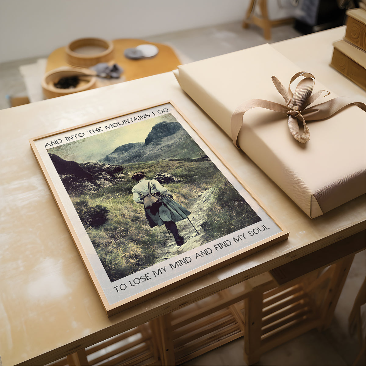 Poster of a person in a mountain landscape on a table with a wrapped gift.