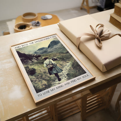 Poster of a person in a mountain landscape on a table with a wrapped gift.