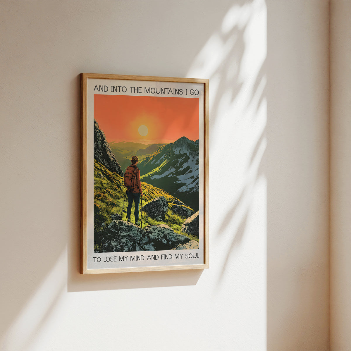 Framed poster of a mountain scene with a person hiking, featuring text on a beige wall.