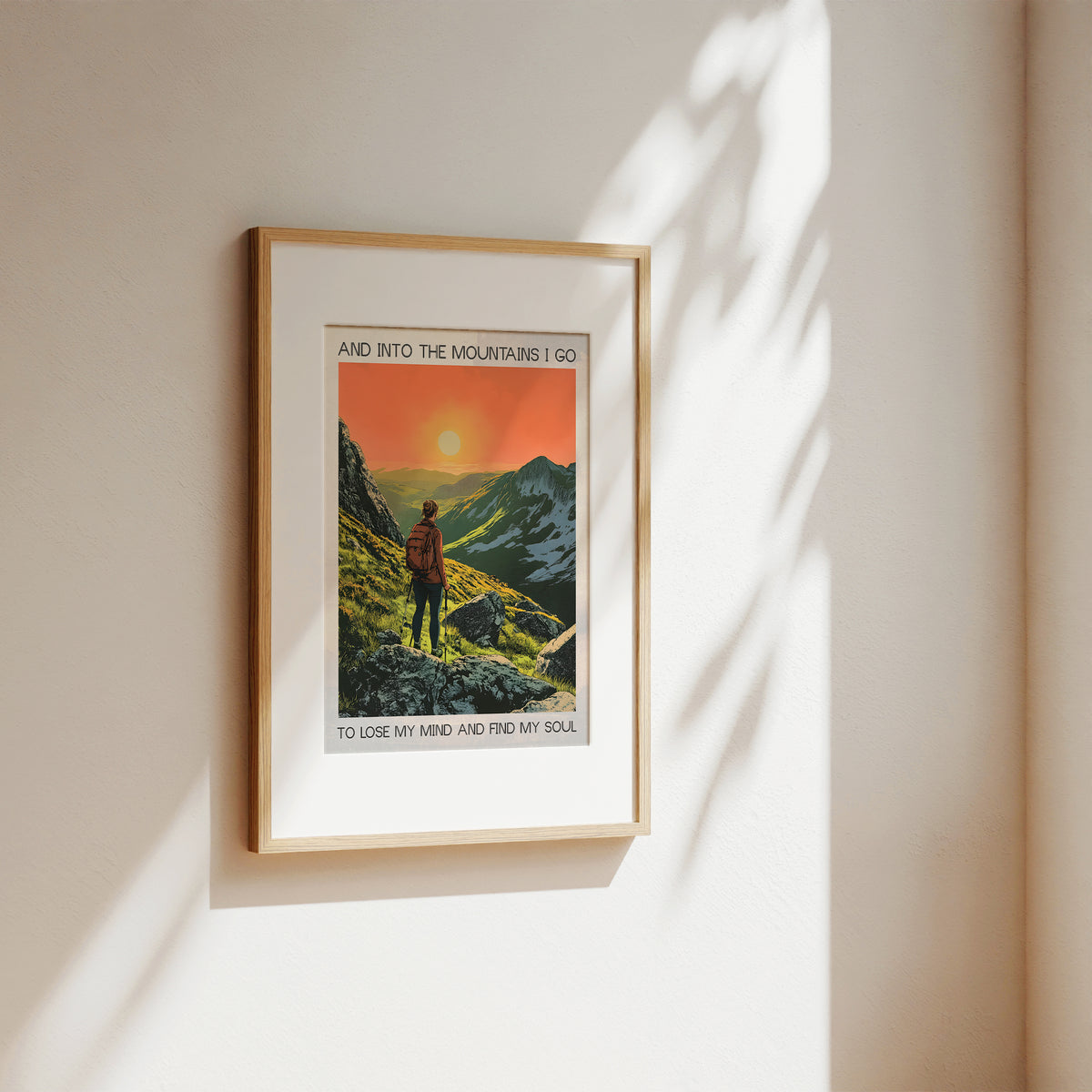 Framed artwork of a mountain scene with a person on a trail, hanging on a wall.