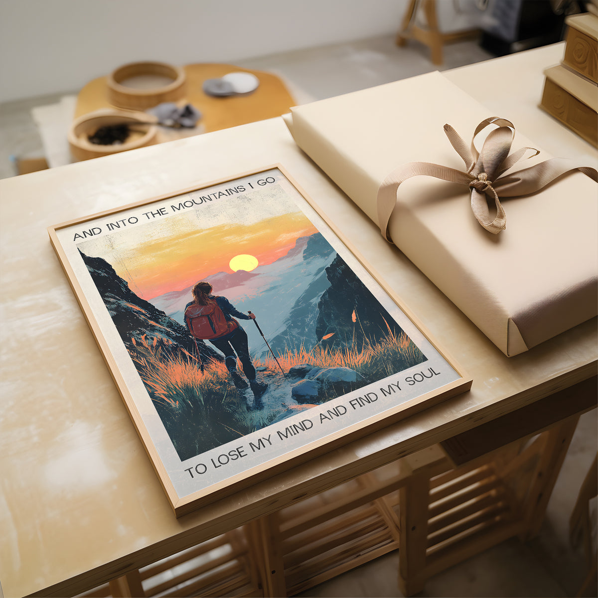 Poster of a hiker in the mountains with a sunset, placed on a table next to a wrapped gift.