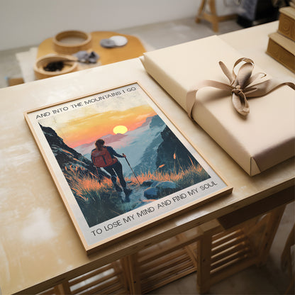 Poster of a hiker in the mountains with a sunset, placed on a table next to a wrapped gift.