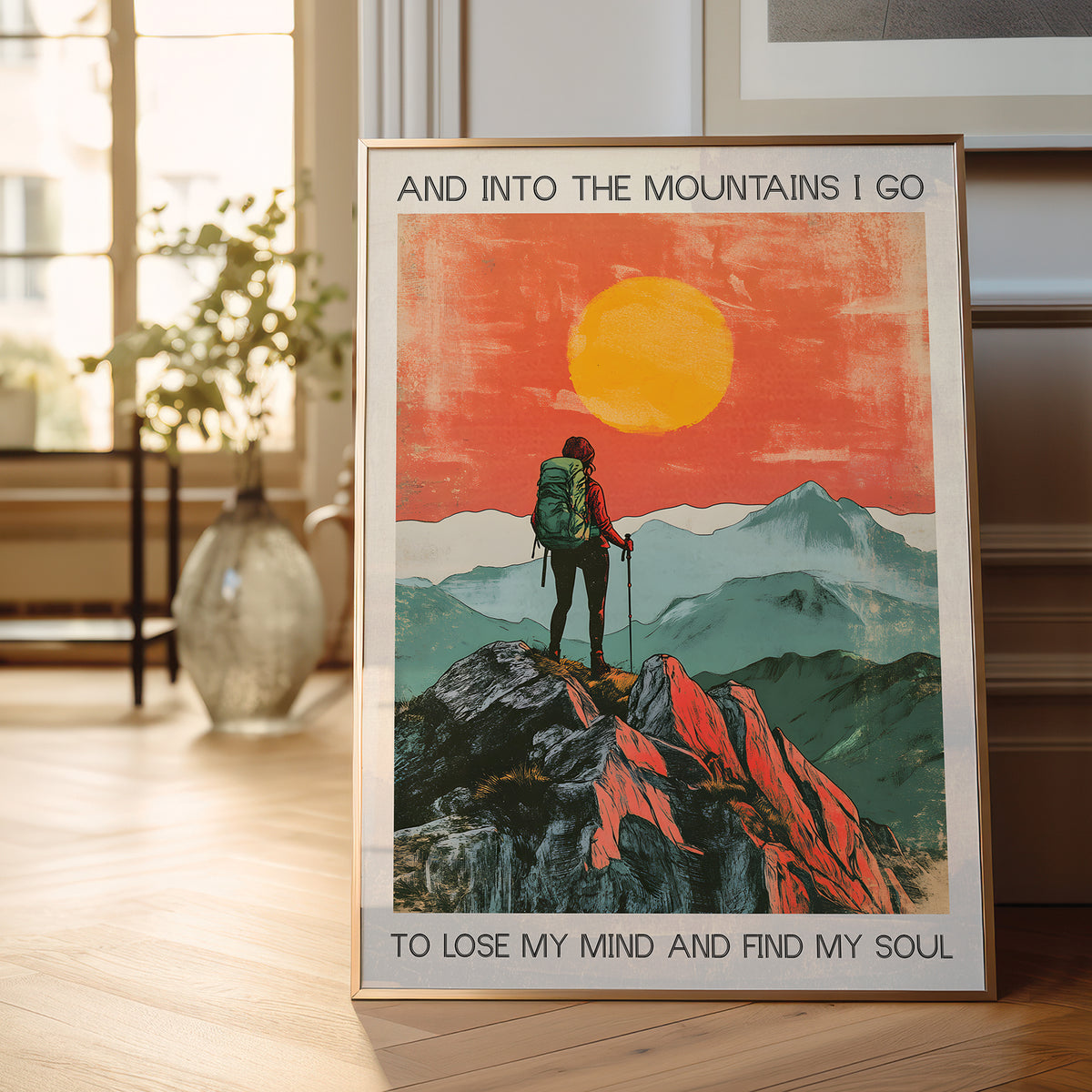 Framed poster of a hiker in the mountains with a sunset, placed on a wooden floor.
