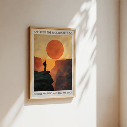 Framed poster of a mountain scene with a silhouette against a sunset, on a wall.