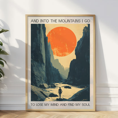 Framed poster of a mountain landscape with a person walking along a river, featuring text 'And into the mountains I go to lose my mind and find my soul'.