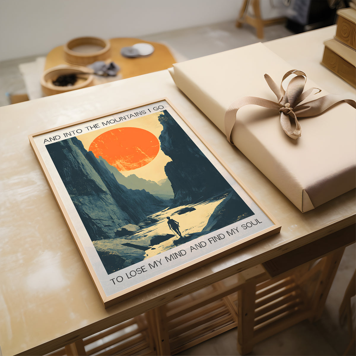 Poster of a mountain scene with text on a table next to a wrapped gift.