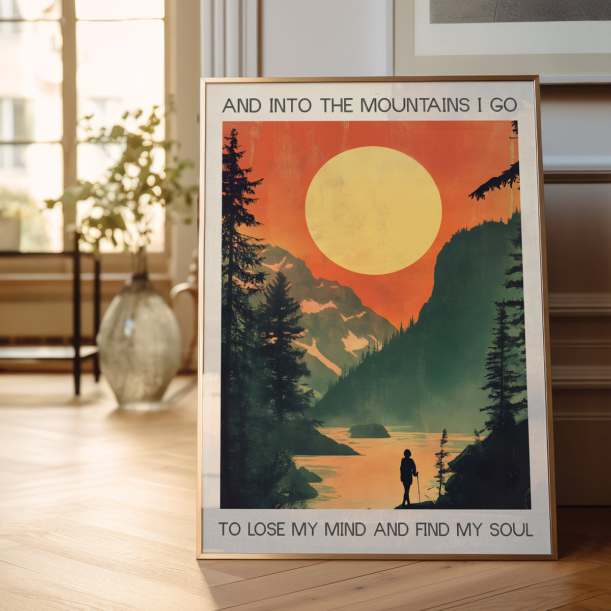 Framed poster with a mountain scene and text in a room with a window and plant.
