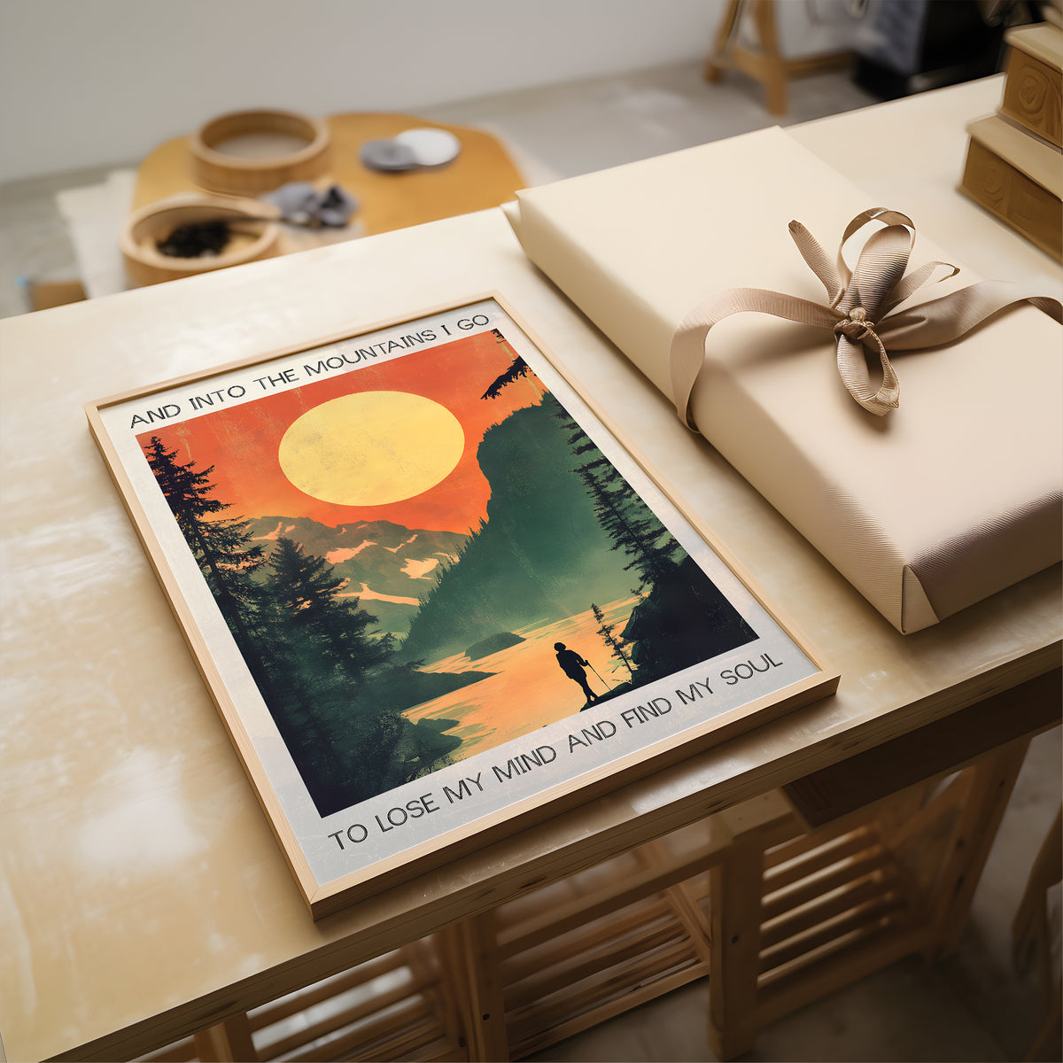 Poster with mountain scene and text on a table with a wrapped gift