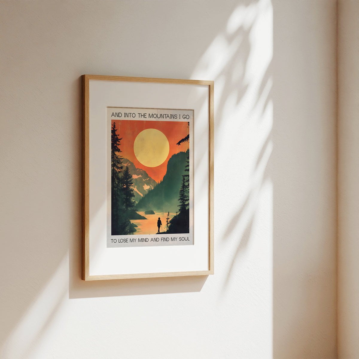 Framed poster with a mountain scene and sunset on a beige wall.