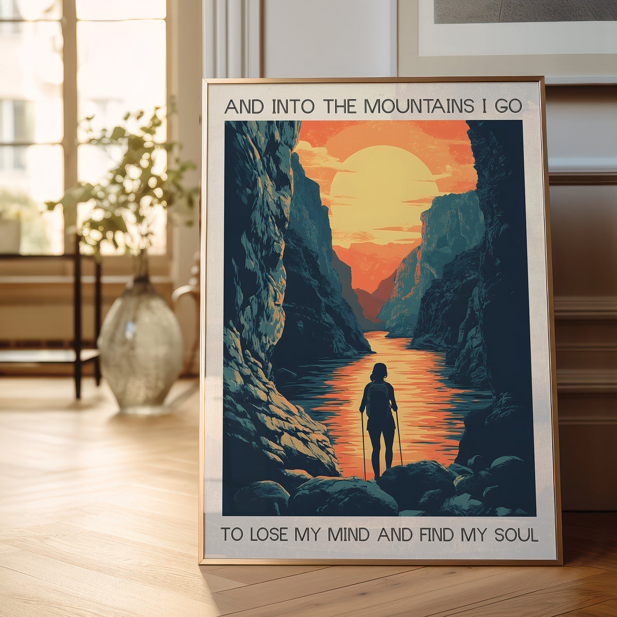 Framed poster of a mountain landscape with a person walking, placed on a wooden floor.