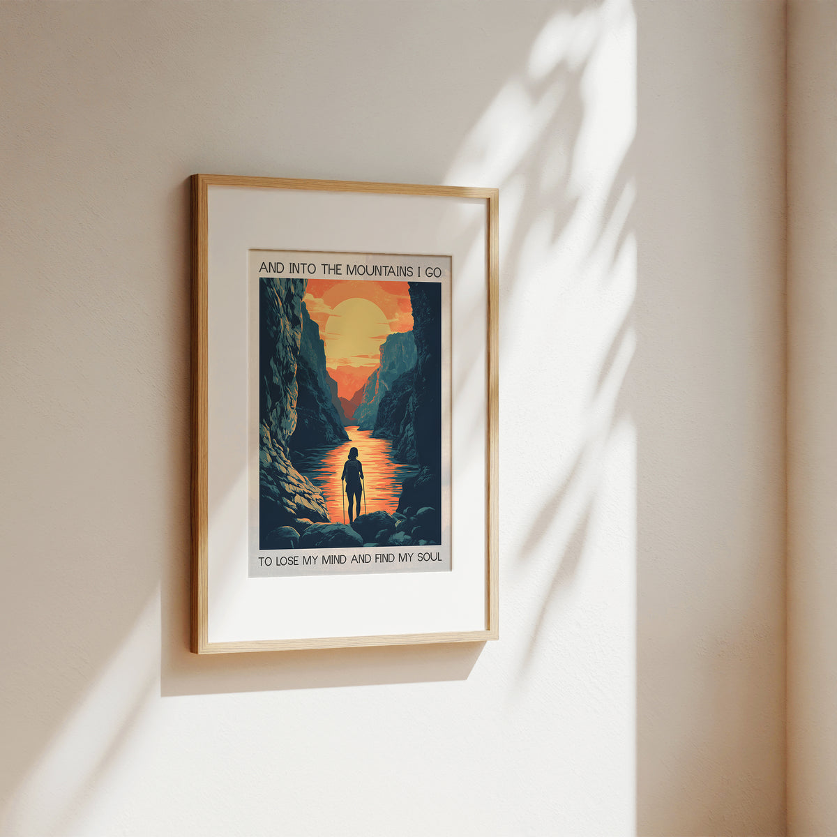 Framed artwork of a mountain scene with a person walking, on a beige wall.