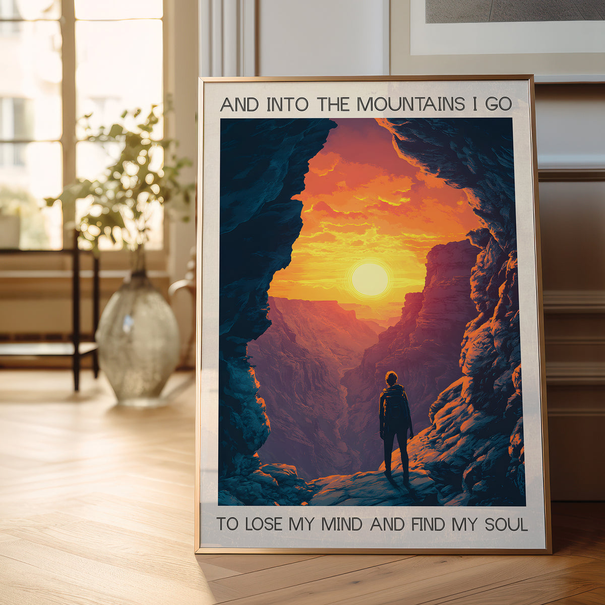 Framed poster of a person standing in a mountain cave with a sunset, placed on a wooden floor.