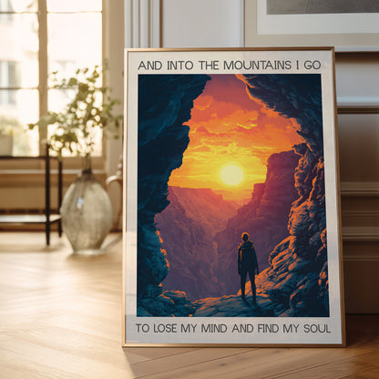 Framed poster of a person standing in a mountain cave with a sunset, placed on a wooden floor.