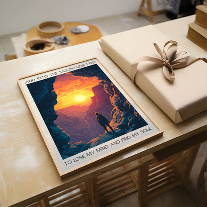 Poster of a person in front of a mountain with a sunset, placed on a table next to a wrapped gift.