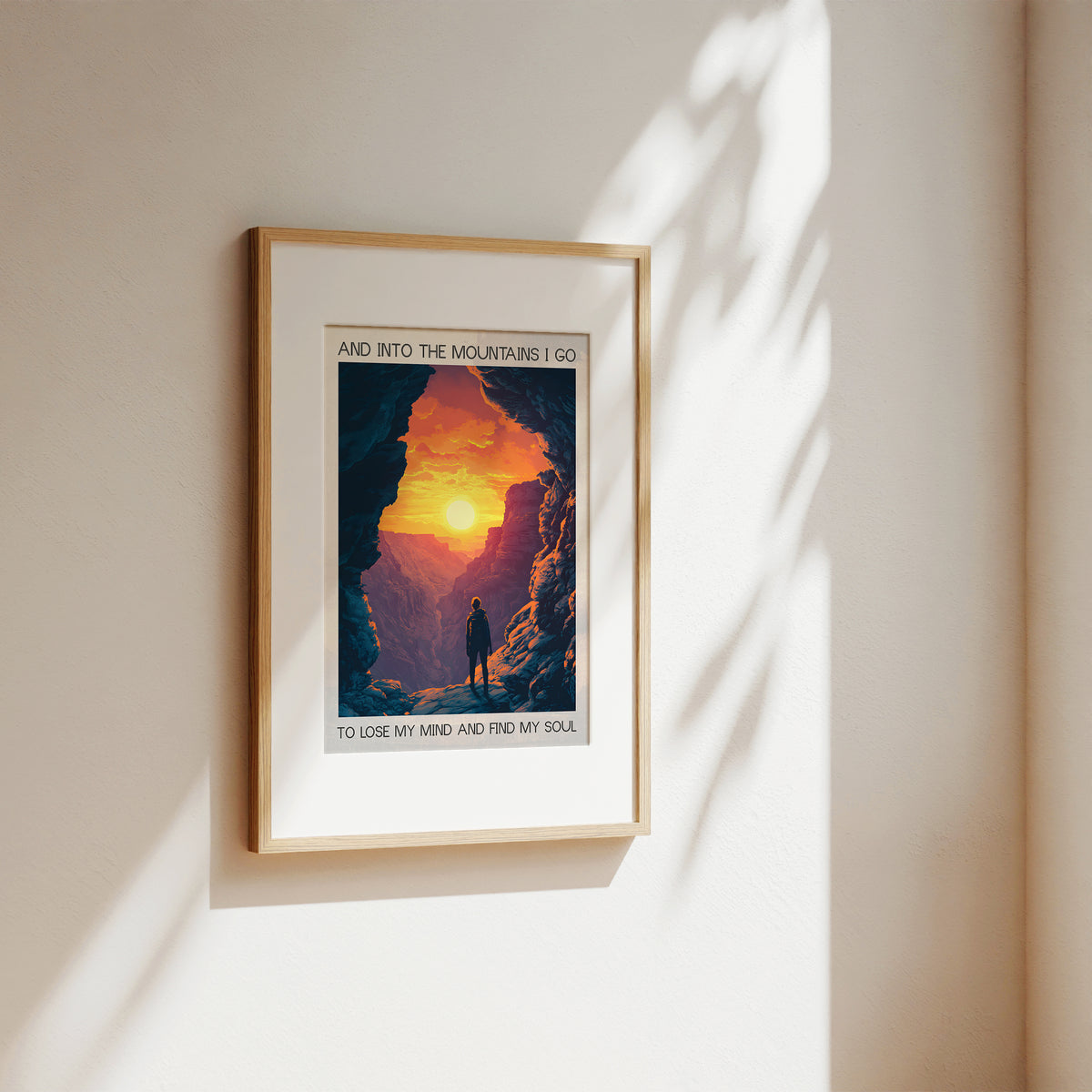 Framed poster of a mountain scene with a person and text on a beige wall.