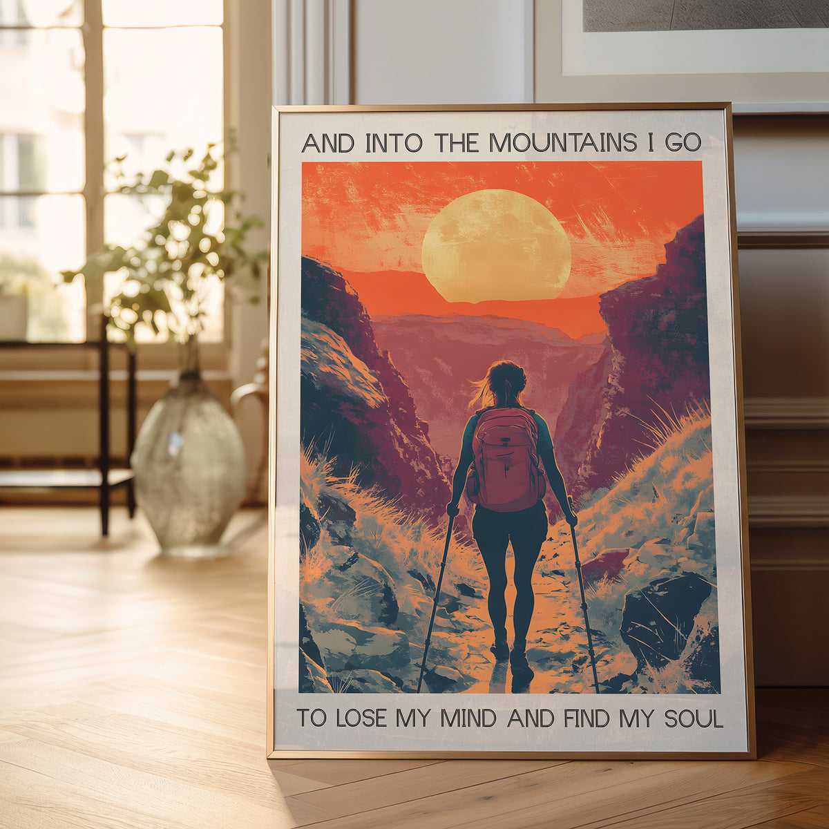 Framed poster of a hiker in the mountains with a sunset, placed on a wooden floor.