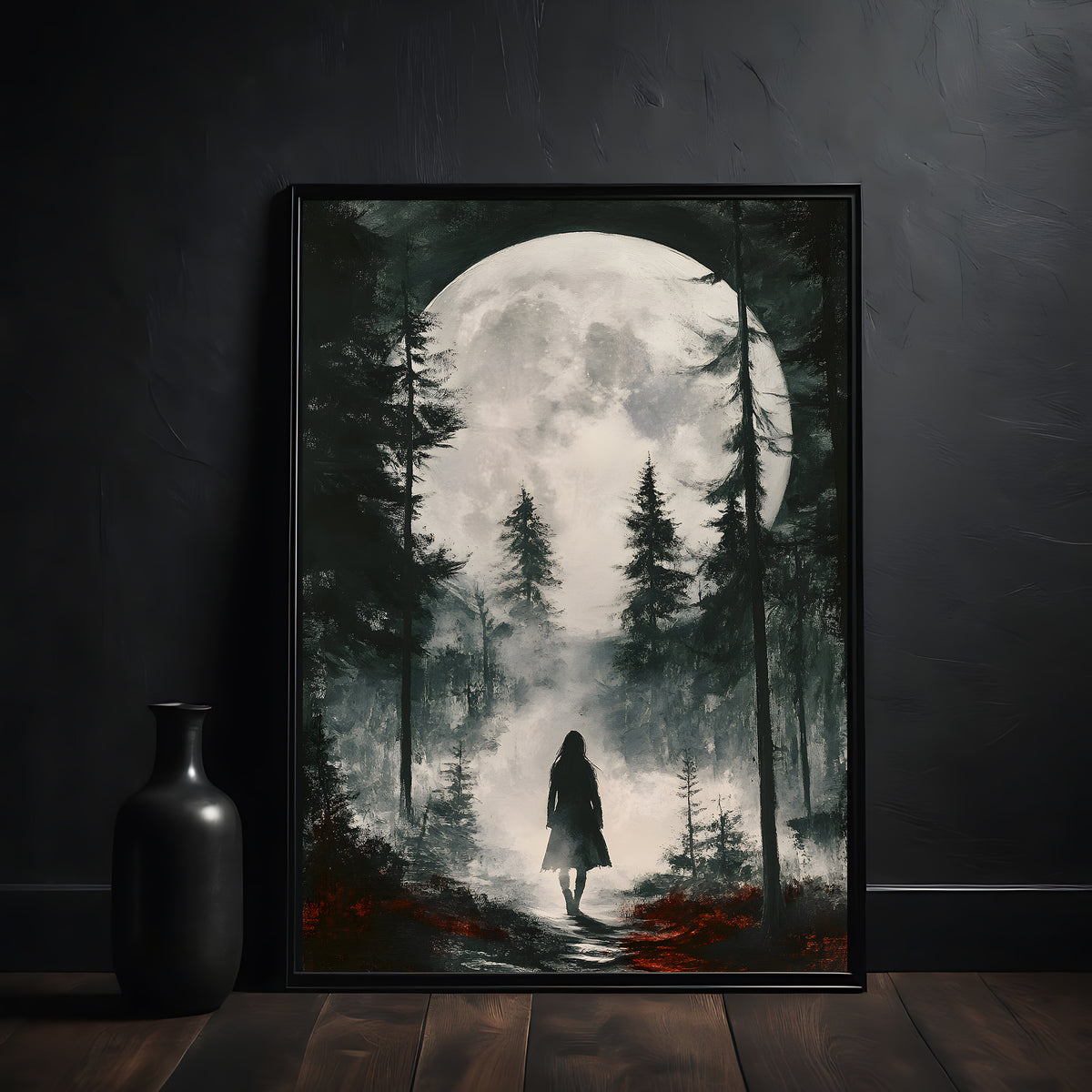 Framed artwork of a person walking through a forest under a large moon, on a dark wall.