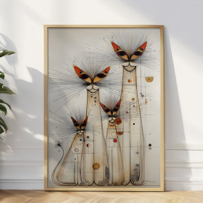 A framed abstract art print featuring stylized cat-like figures with butterfly-like heads, displayed against a white wall on a light wood floor with a plant leaf visible at the left edge.