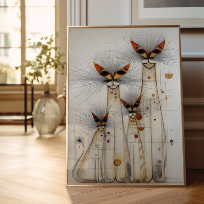 A framed abstract art print featuring stylized cat silhouettes with radiating line details and small orange, red, and gold accents, leaning against a wall in a softly lit room with wood flooring and a vase in the background.